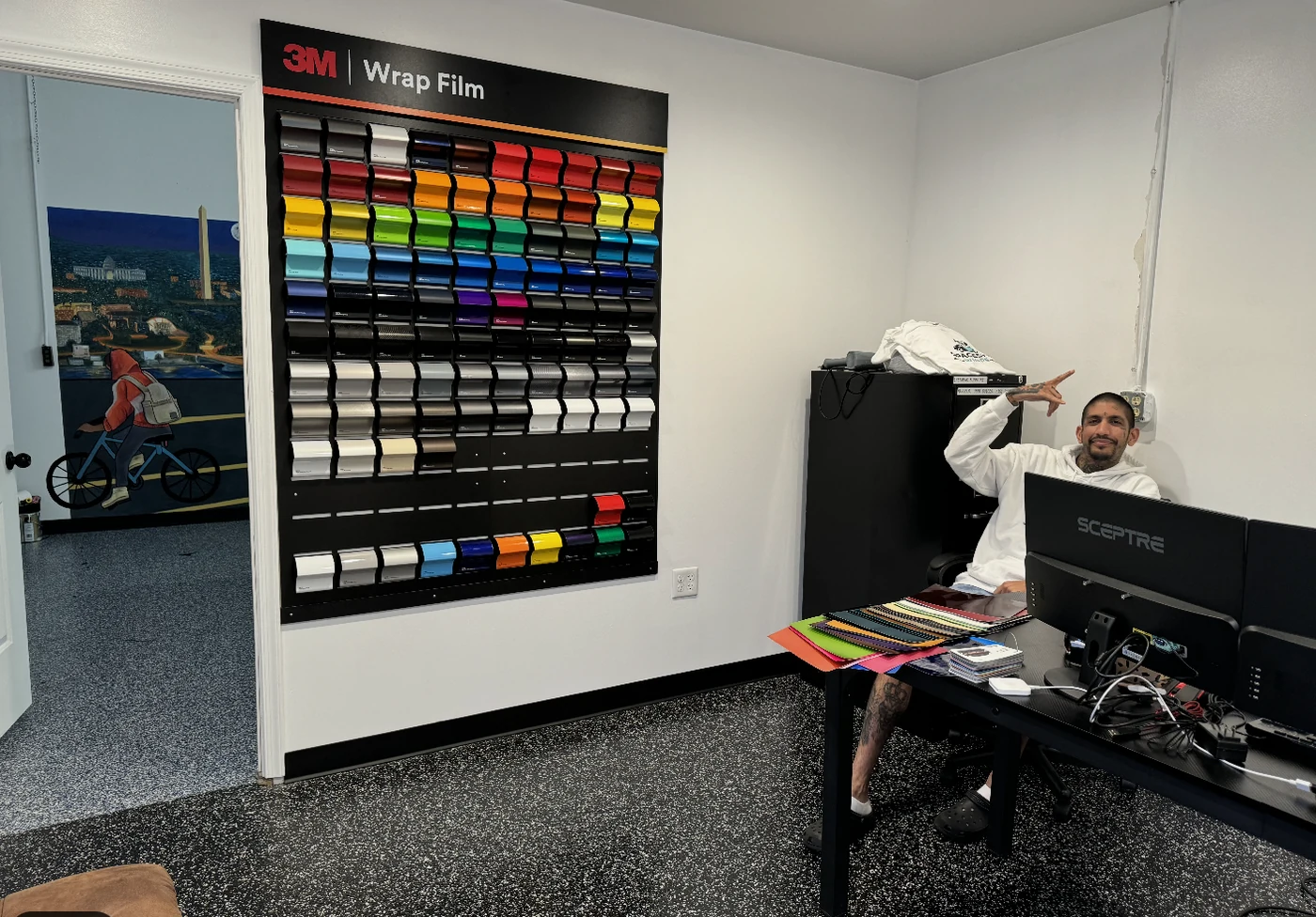 The 3M Wrap Film swatch wall in the consultation room, with sample books on the desk