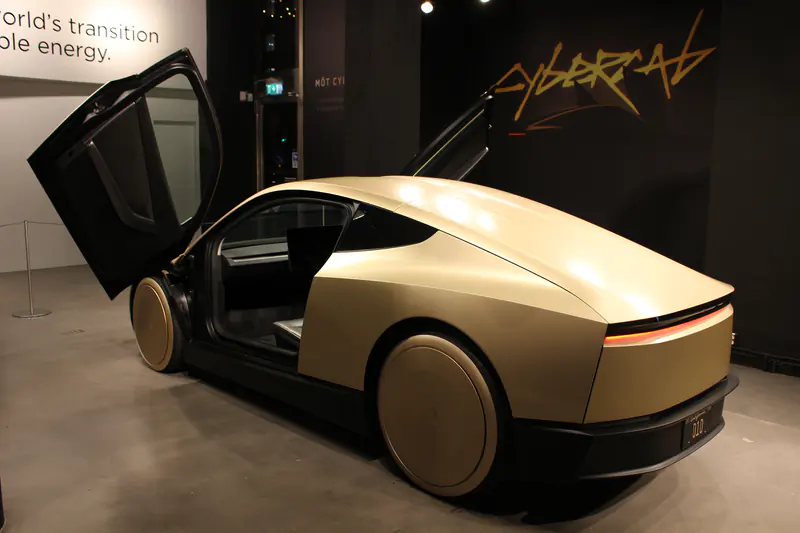 A Tesla Cybercab in its factory gold finish with both doors raised