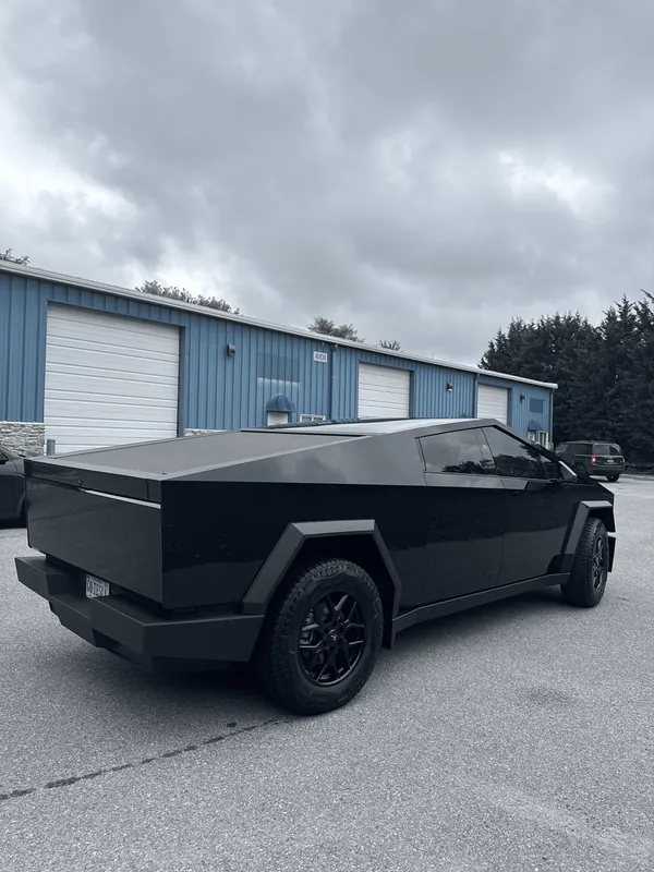 Tesla Cybertruck wrapped in black, parked outside the shop