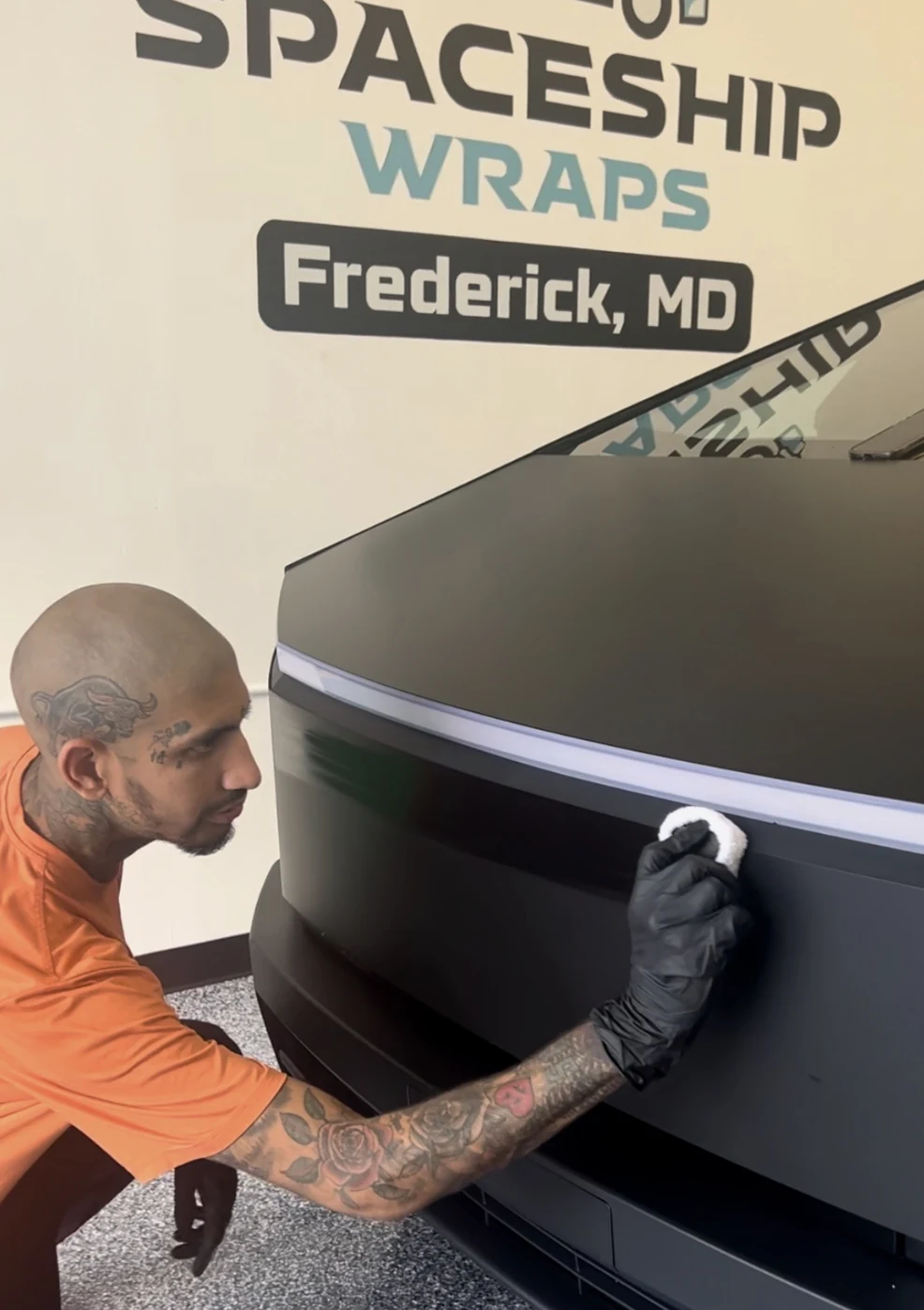 Raoul finishing the front end of a matte black Cybertruck by hand, in the shop