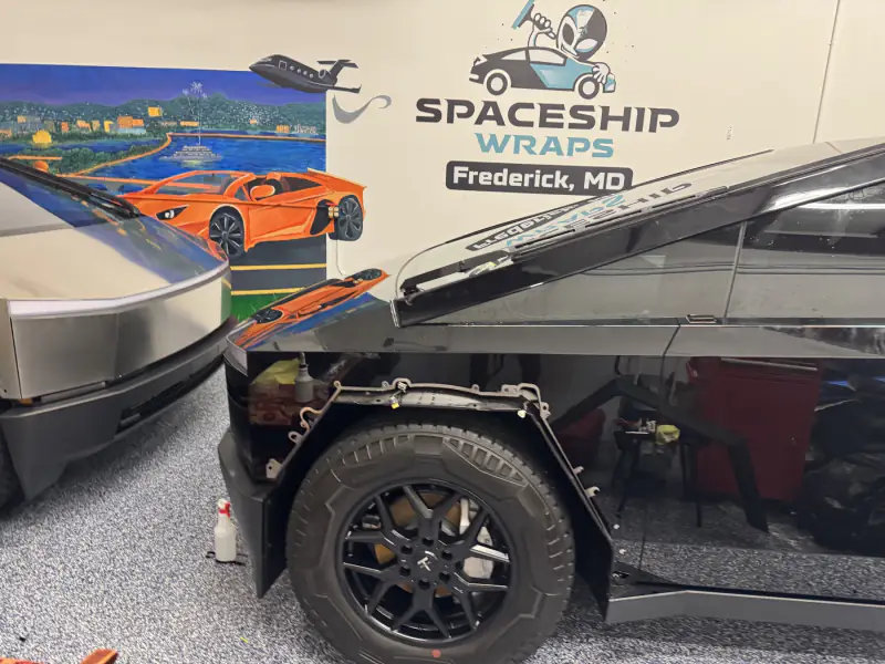 A Cybertruck mid-install with the wheel arch trim removed so film can be wrapped behind it
