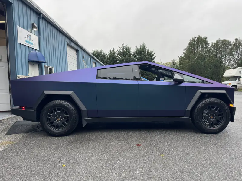 Tesla Cybertruck wrapped in a satin color-shift that reads purple to deep blue, side profile outside the bay
