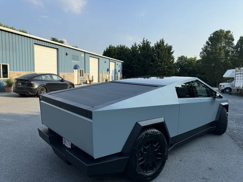 Tesla Cybertruck in stainless finish parked outside the shop building