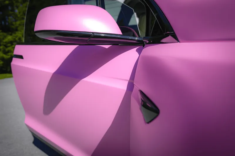 Detail of wrapped film tucked along a pink Tesla door edge