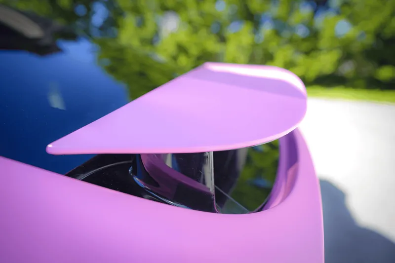 Close-up of a pink wrapped falcon-wing door edge against a green background