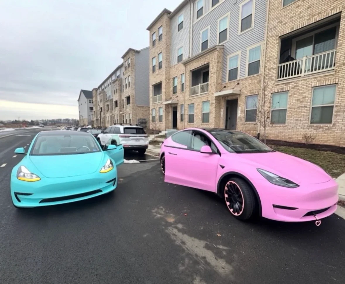 Two Teslas wrapped by the shop on a Northern Virginia street — a Model 3 in 3M Satin Key West and a pink Model Y, doors open