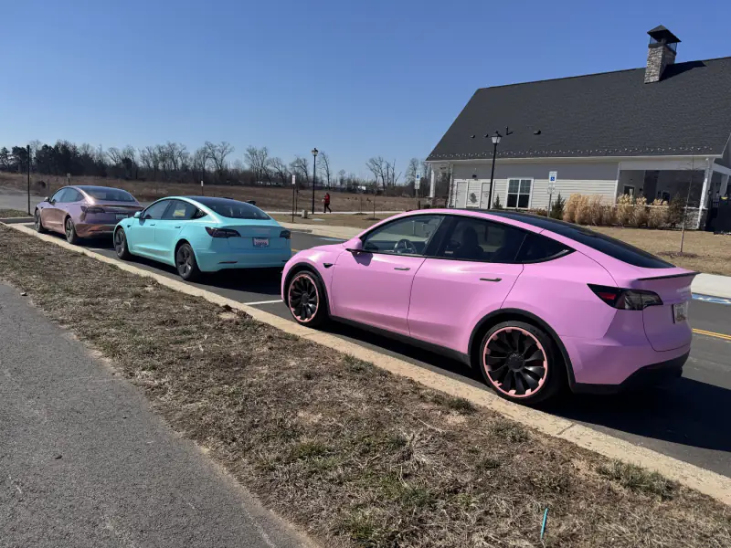 Three wrapped Teslas from behind — rose gold chrome, teal and pink