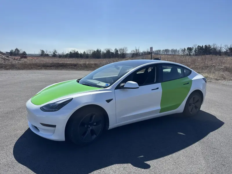 Tesla Model 3 in white with green accent panels across the hood, doors and rear quarter
