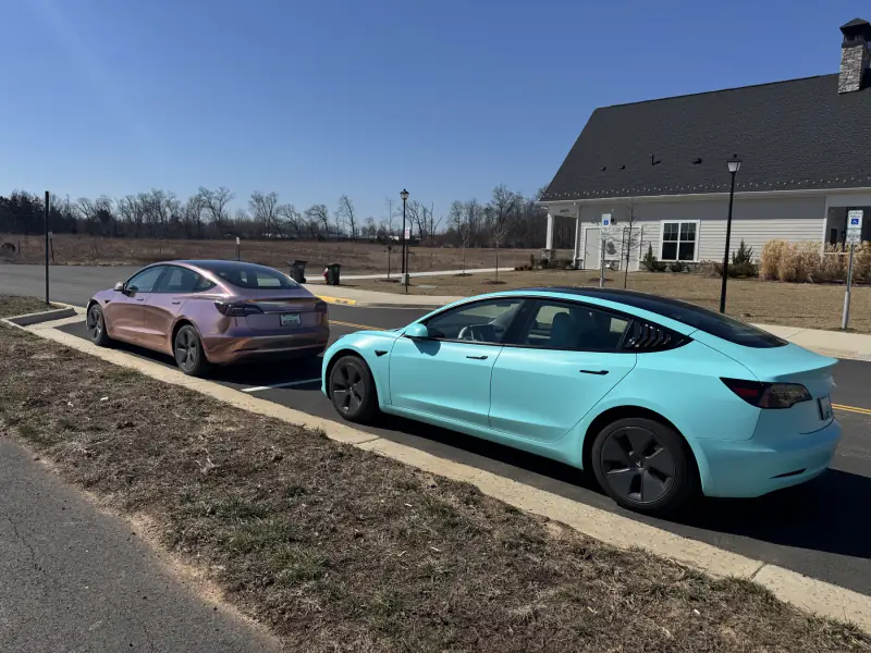 A rose gold chrome Model 3 beside a teal Model 3
