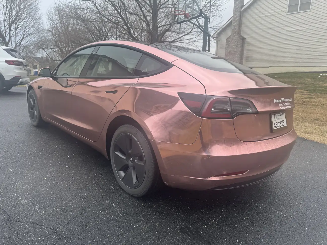 Rear three-quarter of a Model 3 in rose gold chrome, carrying a decal for ModelWrapped, the shop’s earlier name