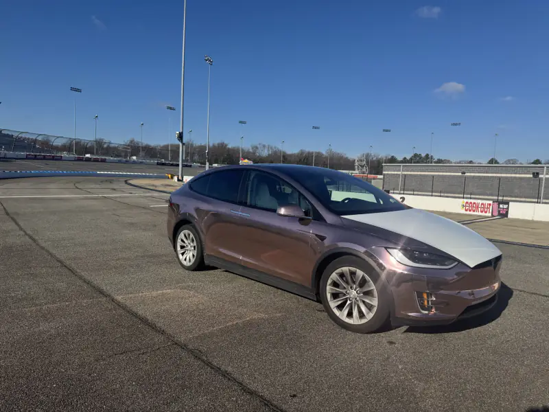 Rose gold chrome Model X on a race track apron in low winter sun