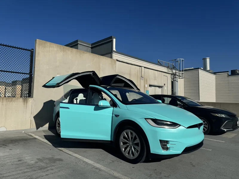 Tesla Model X wrapped in teal with both falcon-wing doors raised