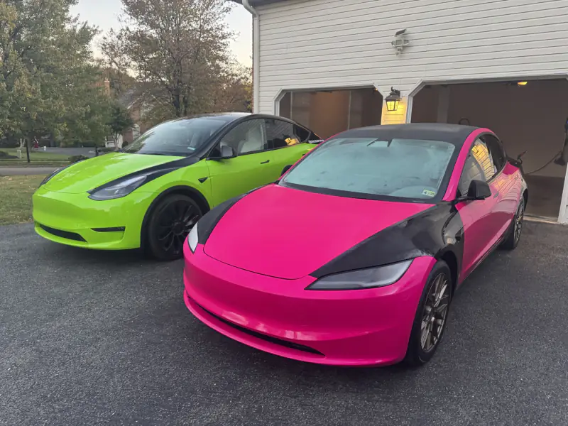 A lime green Model Y and a hot pink Model 3 together on a driveway