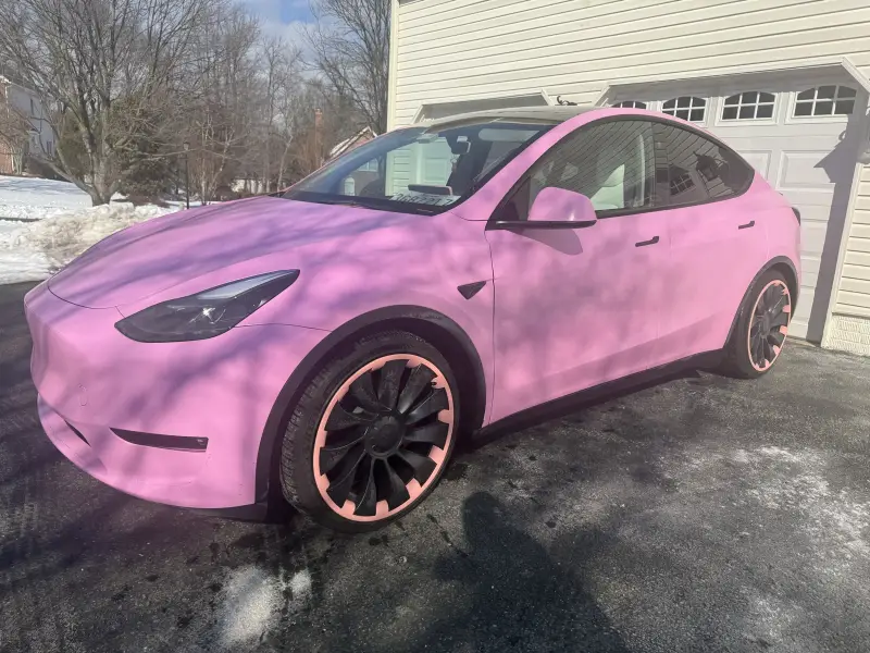 Tesla Model Y wrapped in satin pink, parked on a driveway, with pink accents on the wheels