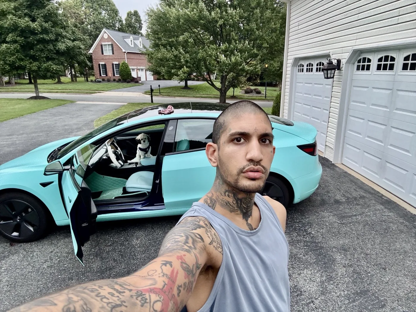 Raoul beside the shop’s Model 3 in 3M Satin Key West, driver’s door open, on a driveway